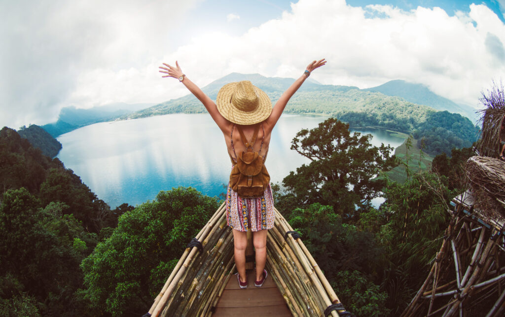 Happy female hiker standing on a cliff with her arms up in the air feeling free