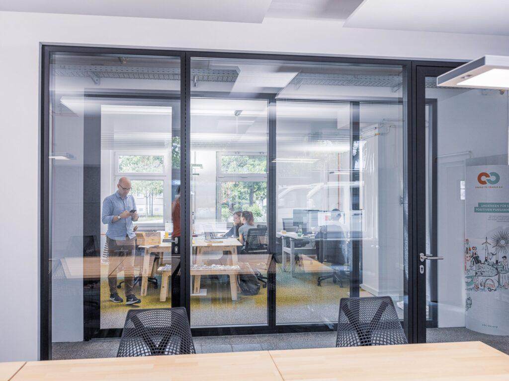 The office of the Cradle to Cradle Lab in Germany. The photo shows people at their desks behind a glass partition.