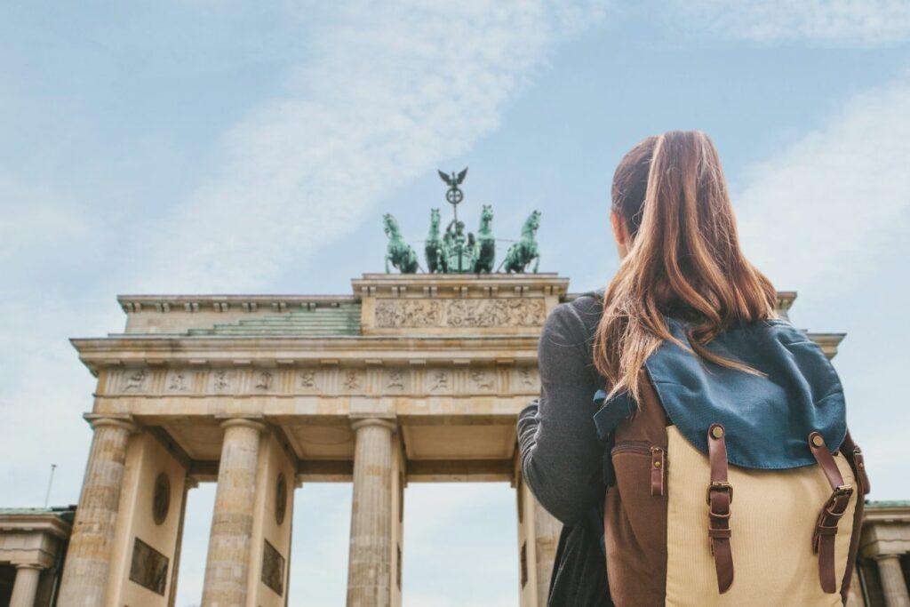 Sustainable travel in Berlin Brandenburg Gate. Woman with backpack in front of it