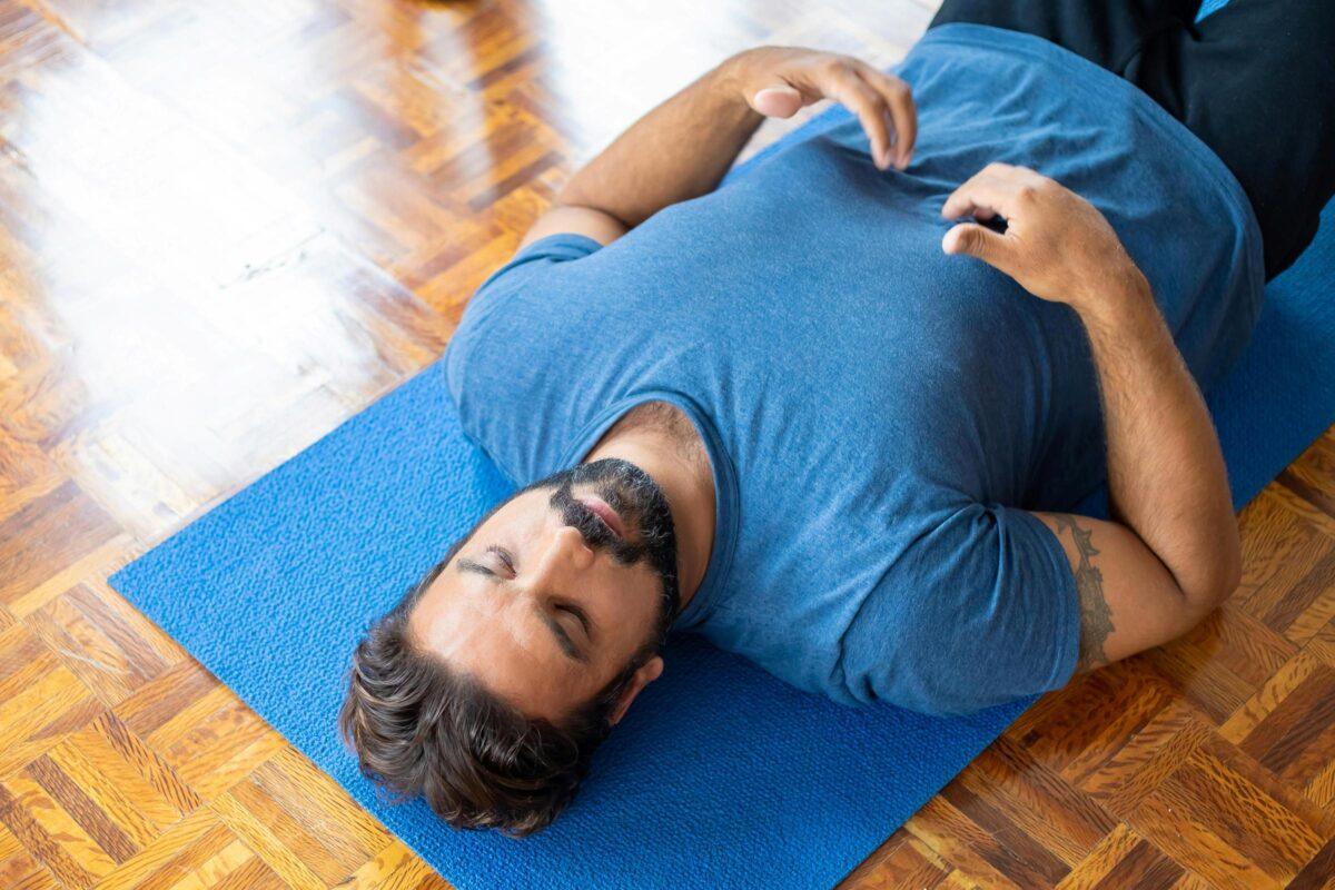 A man is lying on his back and doing breathwork