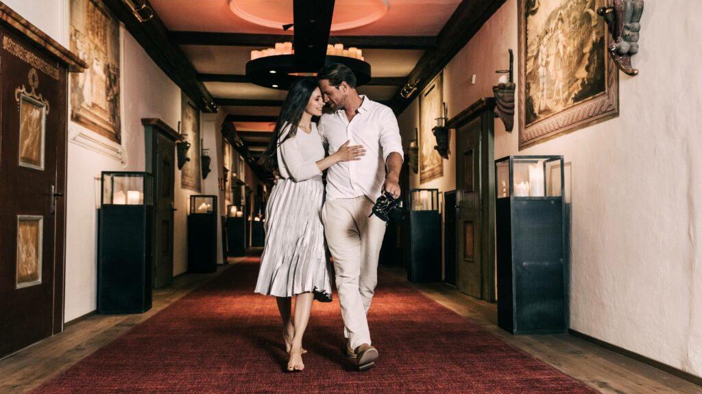 A couple in love in the hallway of the Hotel Klosterbräu. He is carrying her dancing shoes.