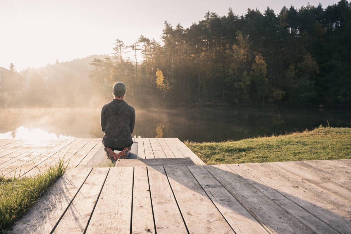 Man in a meditative pose on the dock at Lake Wolsgruben