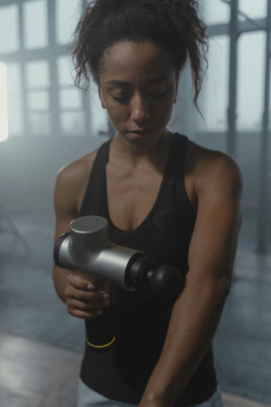 Woman with massage gun at the gym
