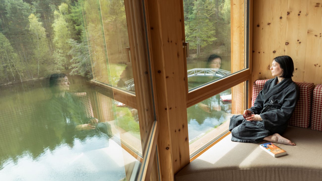 Frau im nachhaltigen Hotelzimmer genießt Blick auf den See in Südtirol