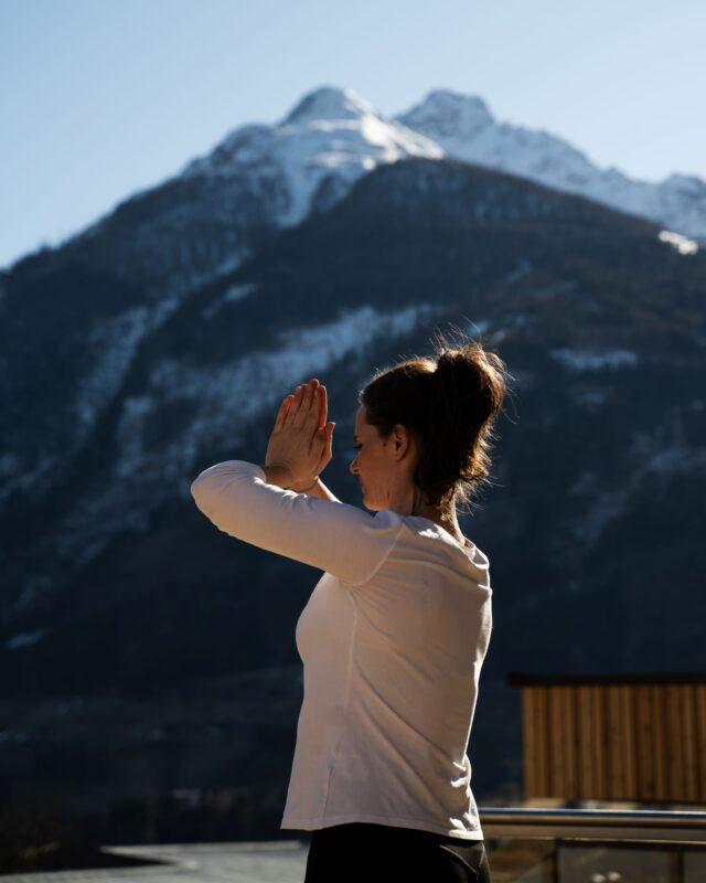 A woman in a yoga pose gazes at the mountains in East Tyrol