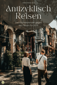 Zwei Personen gehen eine enge, von alten Gebäuden gesäumte Straße entlang, die von Pflanzen und Laternen belebt wird