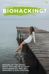 Woman in a white dress sits at the end of a wooden jetty, dangling her feet in the water in front of a calm lake.