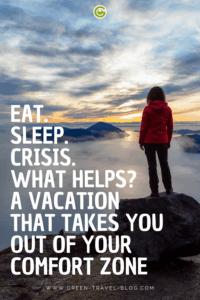 A person wearing a red jacket stands on a rock, gazing out at a cloud-covered mountain landscape in the morning or evening light. In the foreground is a large block of white text that reads: ‘EAT. SLEEP. CRISIS. WHAT HELPS? A VACATION THAT TAKES YOU OUT OF YOUR COMFORT ZONE’.