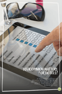 A finger taps on a tablet displaying a guest review survey, next to a pair of sunglasses and a glass