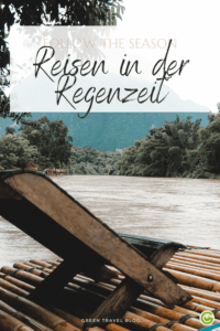 Bambusterrasse an einem Fluss, umgeben von üppig grünen Bäumen und fernen Hügeln unter einem bewölkten Himmel. Der Text lautet: „Reisen in der Regenzeit“.