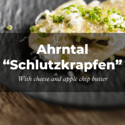 Close-up of Ahrntal Schlutzkrapfen with chopped chives and grated cheese on a dark plate