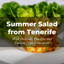 Summer salad with avocado, papaya, and passion fruit vinaigrette on a white plate against a bed of green lettuce